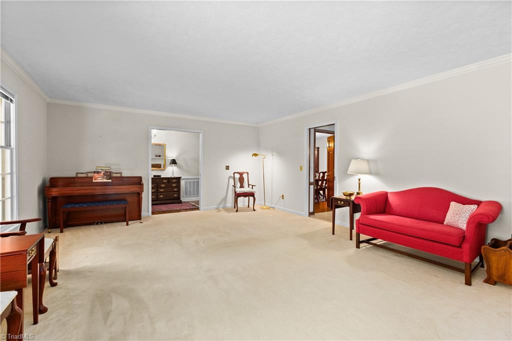 Living room with a red sofa, wooden piano, and cream carpet.