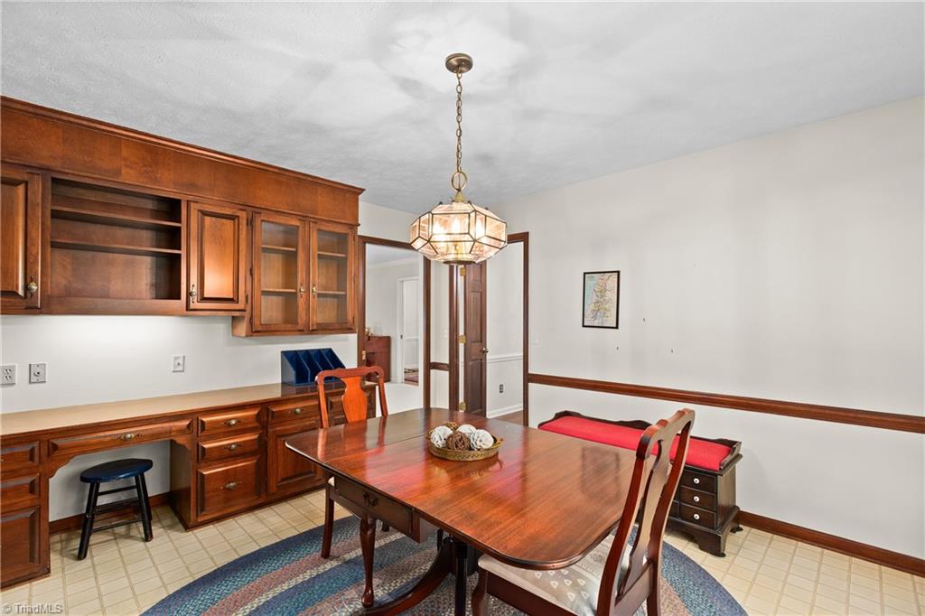 Dining room with built-in wooden cabinetry, a large table, and pendant lighting.