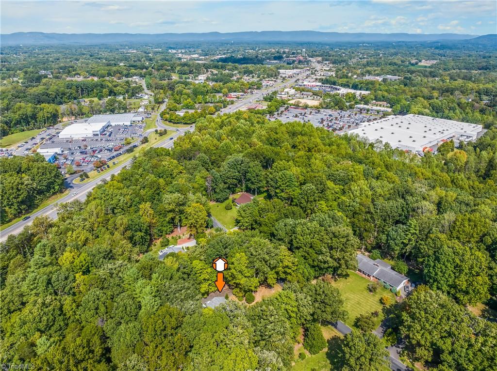 Aerial view of a wooded property marked by an orange locator, with Mount Airy and distant mountains beyond.