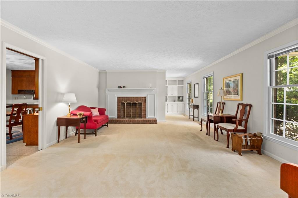 Living room with brick fireplace, built-in shelving, tall windows, and a red sofa.