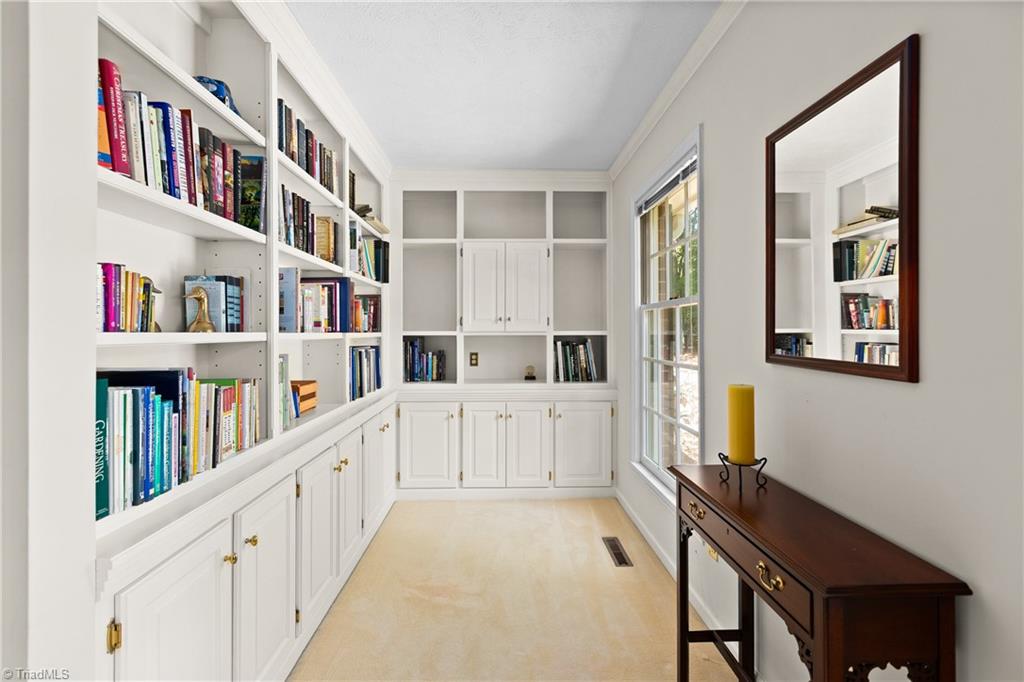 Home library with white built-in bookshelves, a large window, and a dark wood console table.