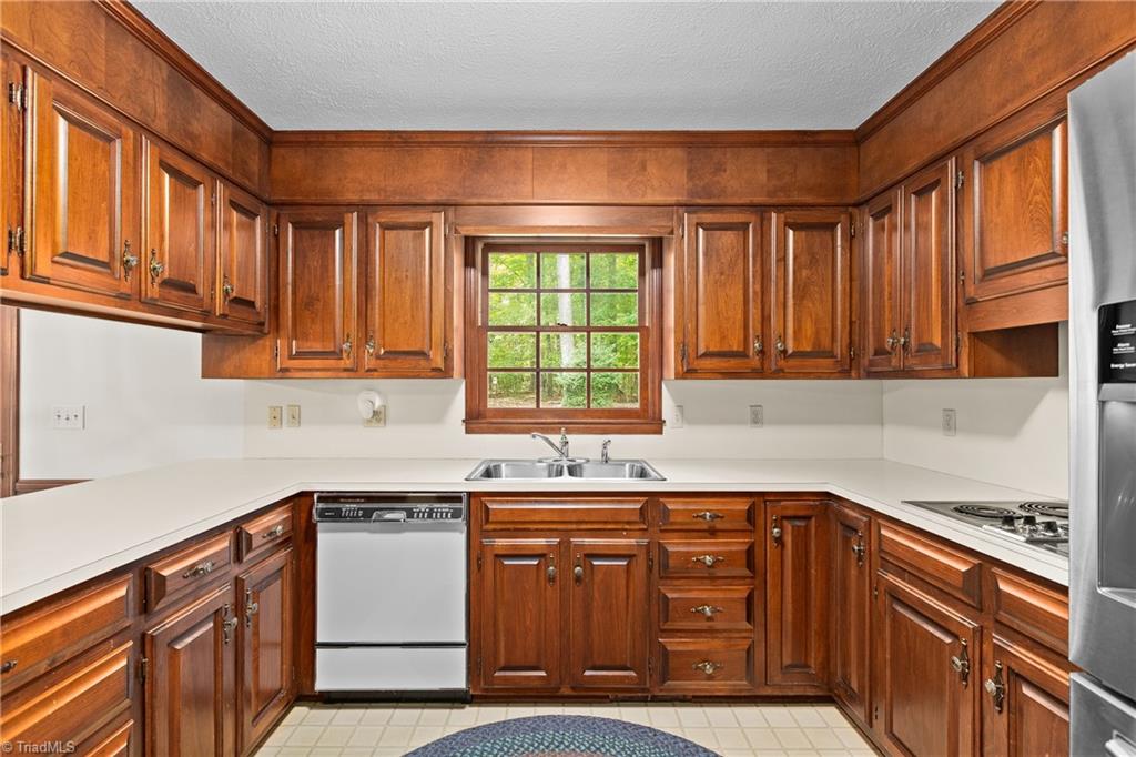 Kitchen with warm wood cabinetry, white countertops, and a window above the sink.