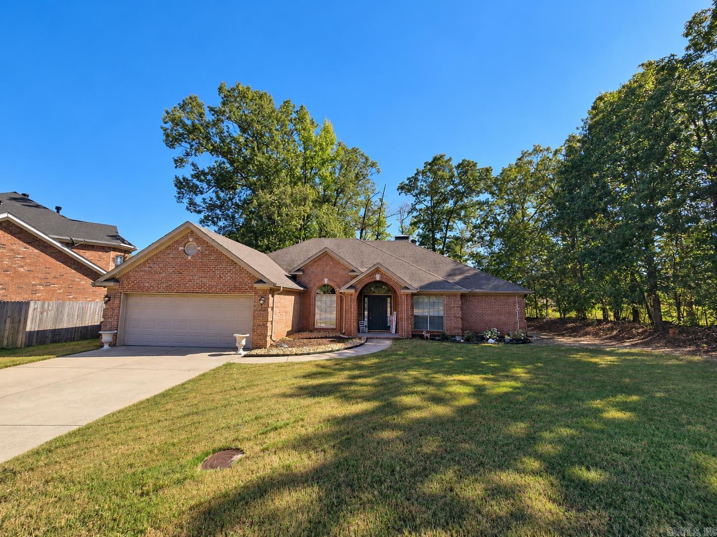 Brick house with a two-car garage and arched entry, set behind a broad lawn and mature trees.