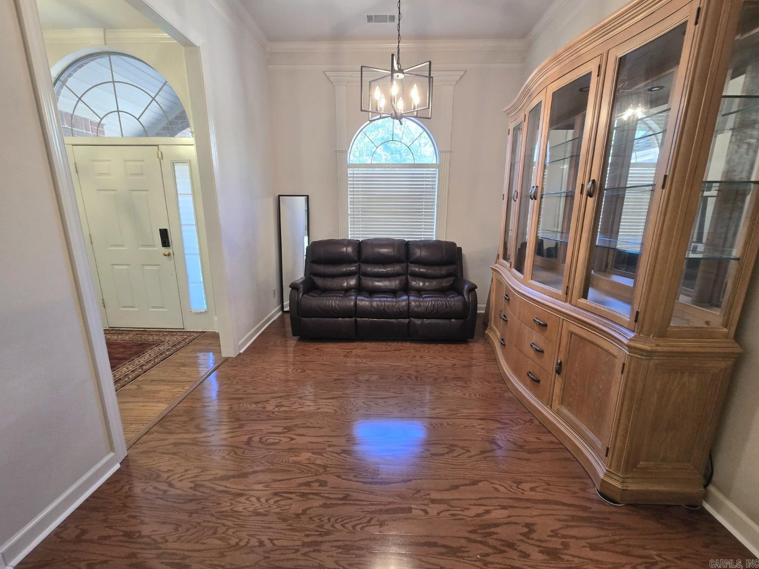 Entry sitting area with a leather sofa, curved wooden cabinet, and arched windows.
