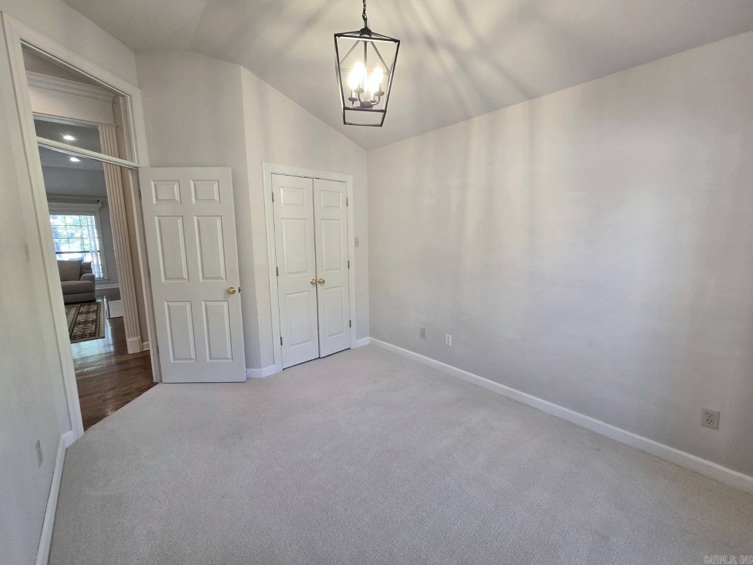 Empty bedroom with gray carpet, a double-door closet, and a hanging lantern-style light.