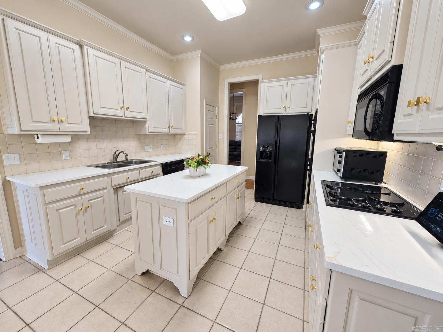 Kitchen with white cabinetry, central island, tiled floors, and black appliances.