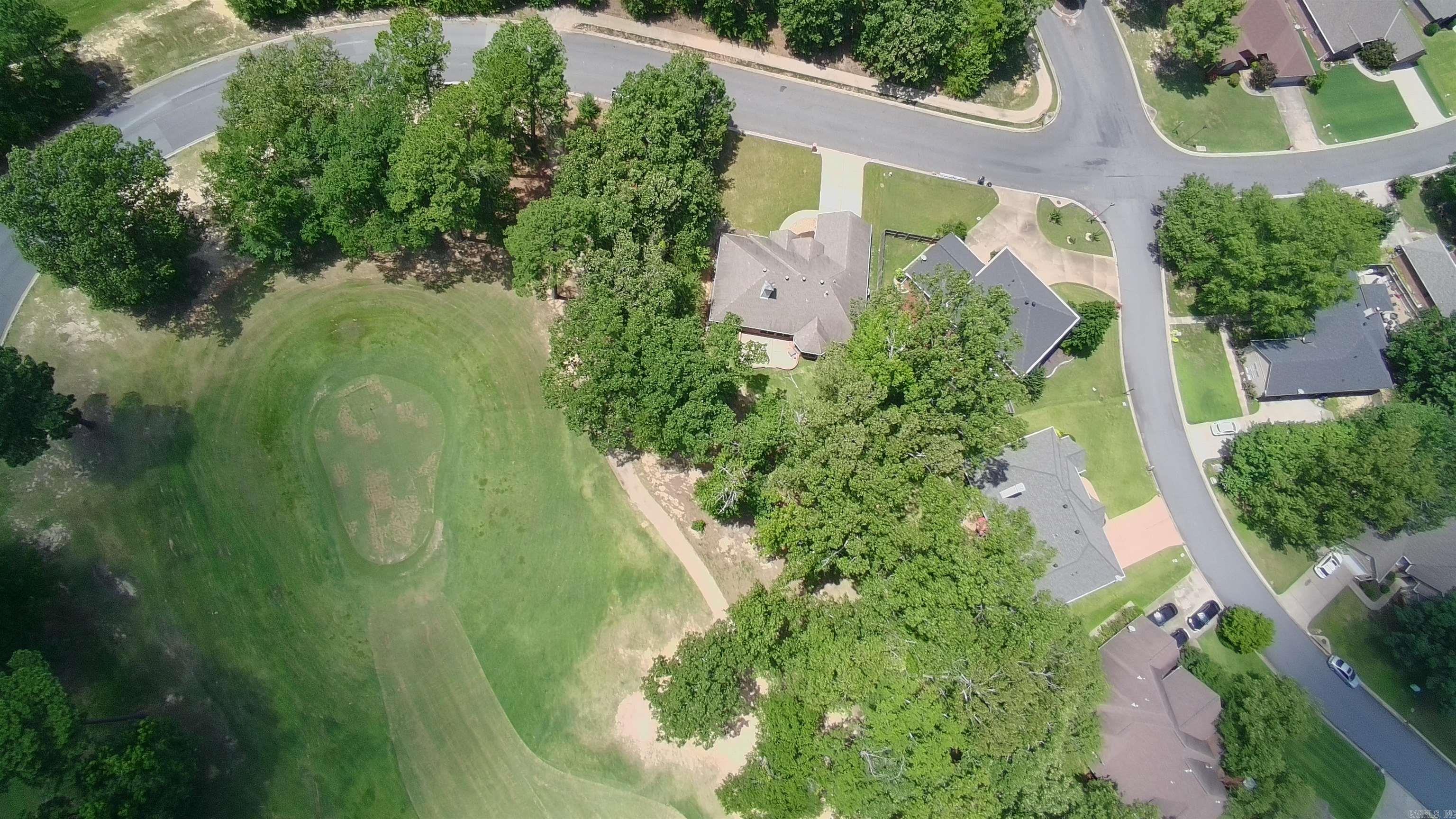 Aerial view of 210 Deauville Drive beside a broad green space and tree-lined neighborhood.