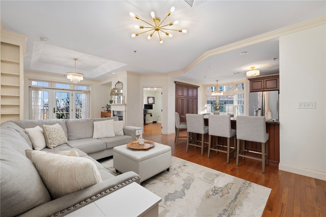 Open-plan living room and kitchen with a gray sectional, white ottoman, and dark wood island cabinetry.