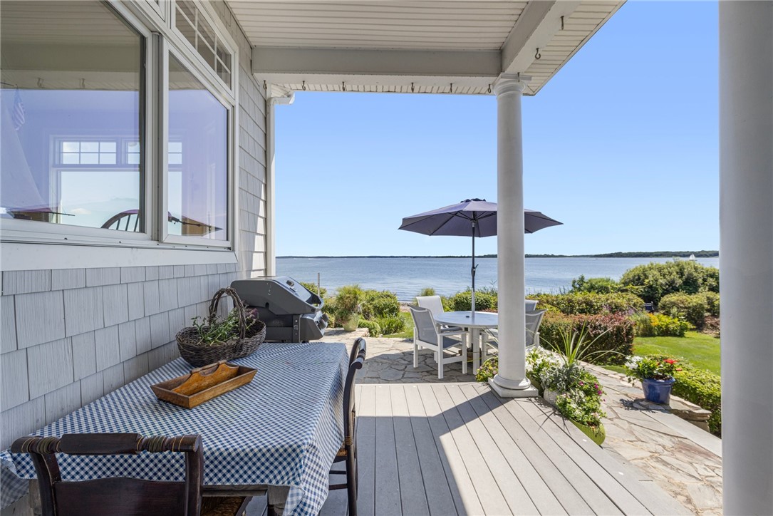 Covered waterfront deck with outdoor dining table, grill, and views across the water.