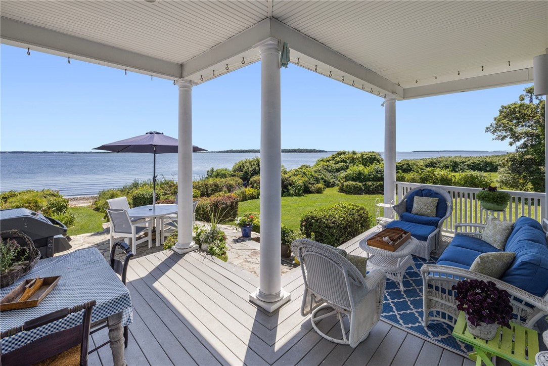 Covered waterfront deck with dining and lounge seating overlooking the bay.