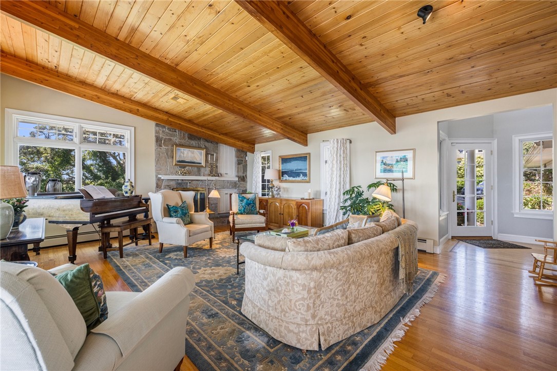 Living room with a vaulted wood-plank ceiling, exposed beams, and a stone fireplace.
