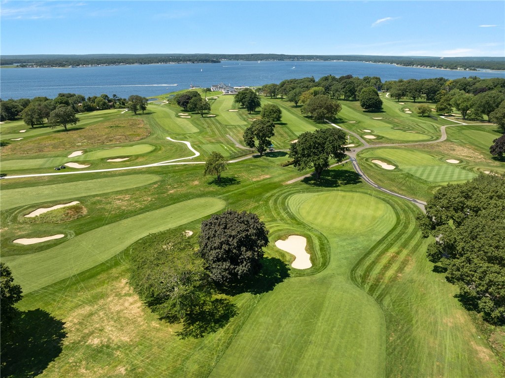 Aerial view of a waterfront golf course with rolling greens, sand bunkers, and tree-lined fairways.