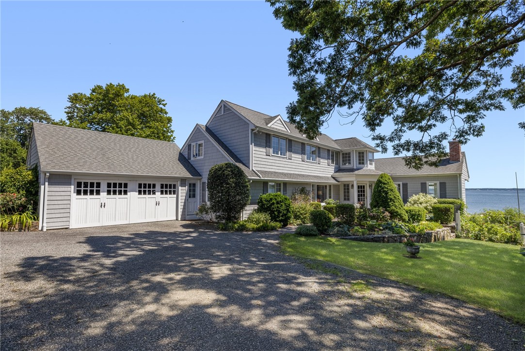 Gray two-story waterfront home with an attached garage and landscaped lawn.