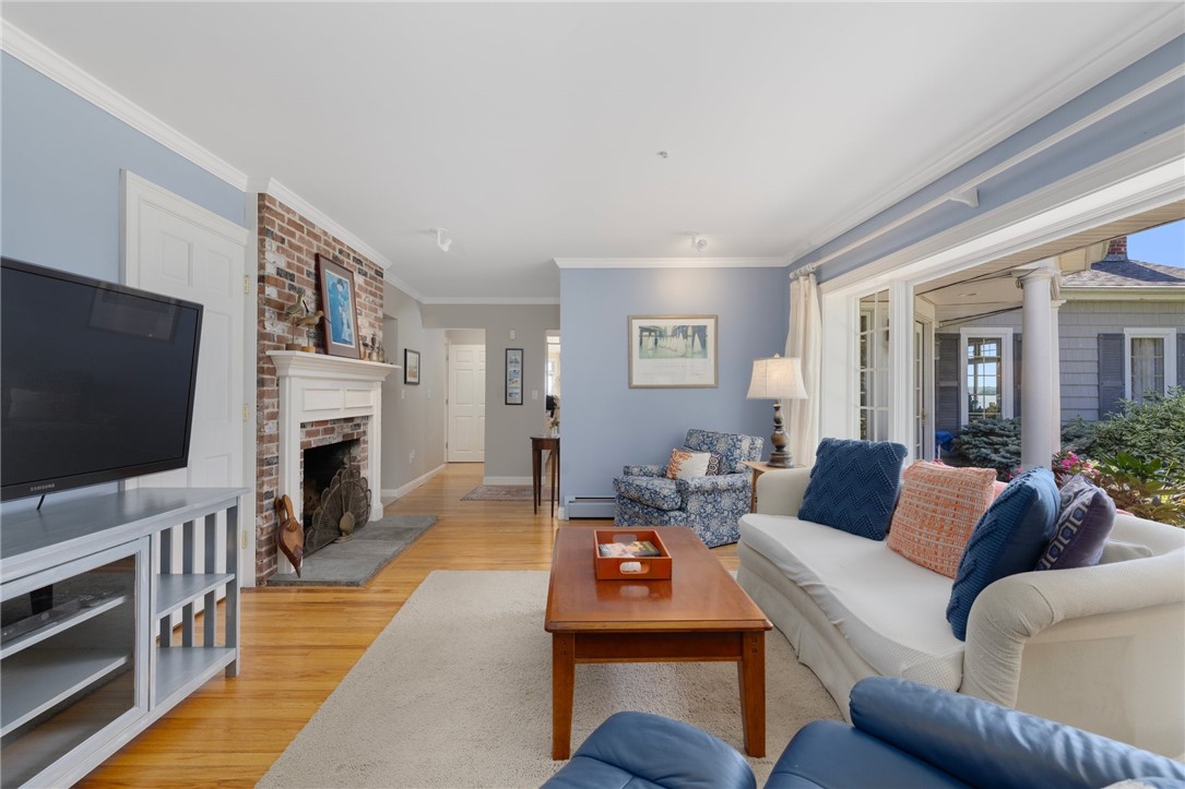 Living room with brick fireplace, hardwood floors, and glass doors opening to a covered patio.