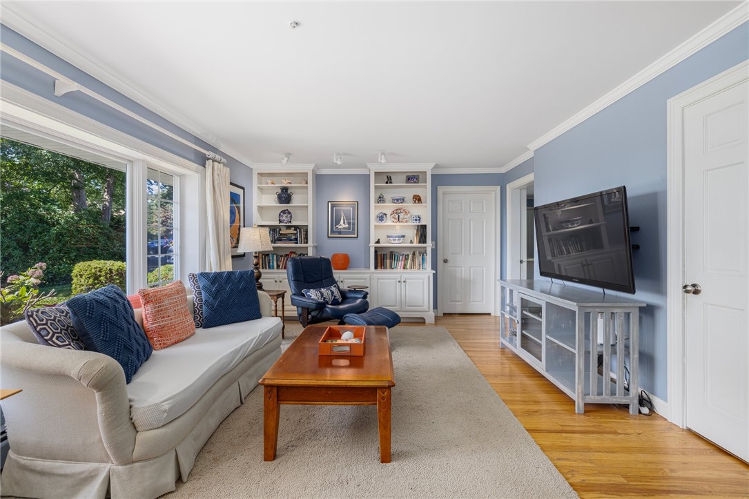 Furnished living room with built-in shelves, blue walls, and large windows overlooking greenery.