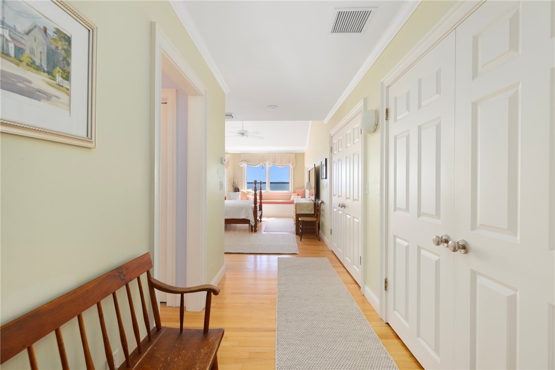 Bright hallway with hardwood floors and white paneled doors leading to a bedroom with a water view.
