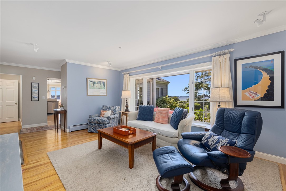 Living room with blue leather recliner, hardwood floors, and windows overlooking the water.