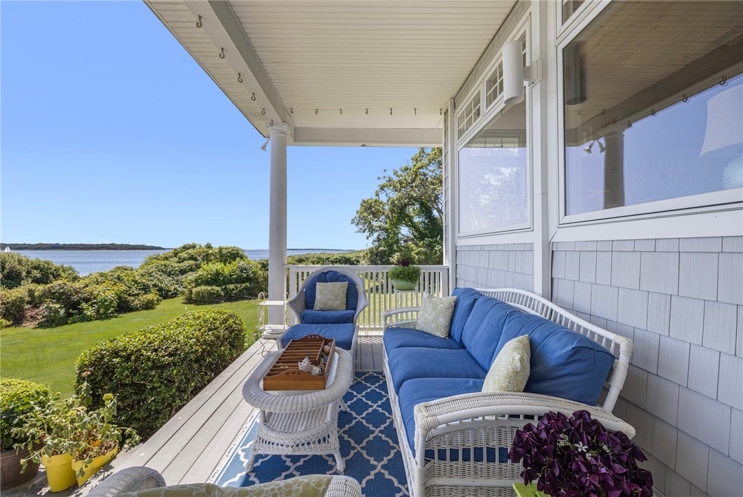 Covered waterfront porch with blue wicker seating and views across the water