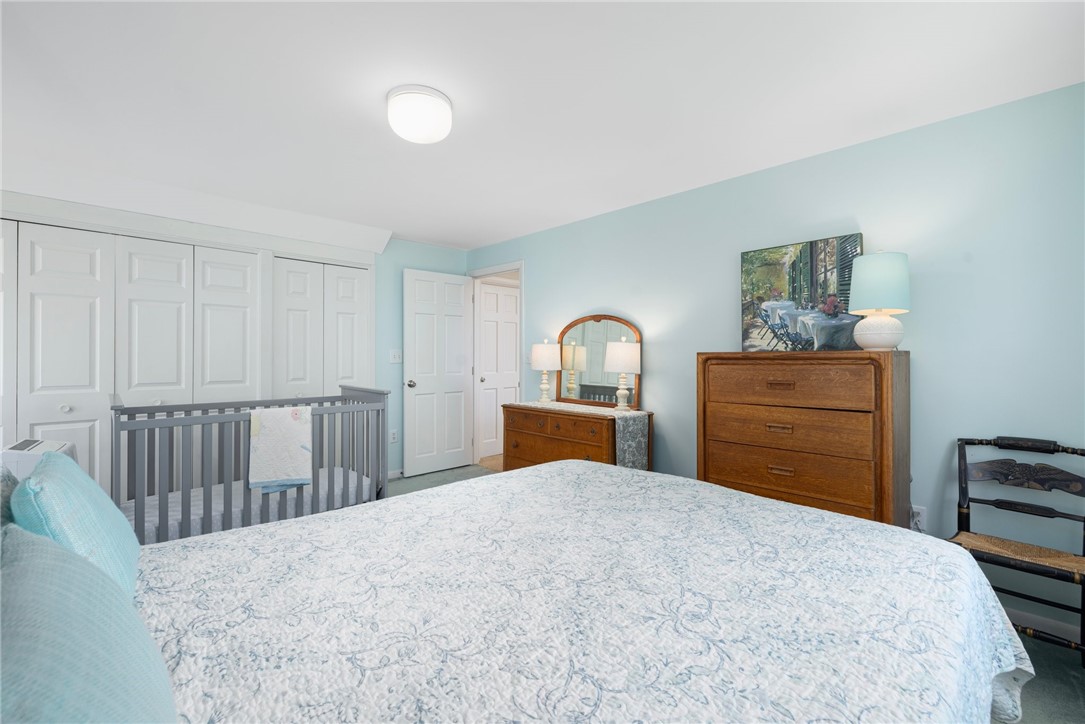 Bedroom with a large bed, wooden dressers, and a gray crib.