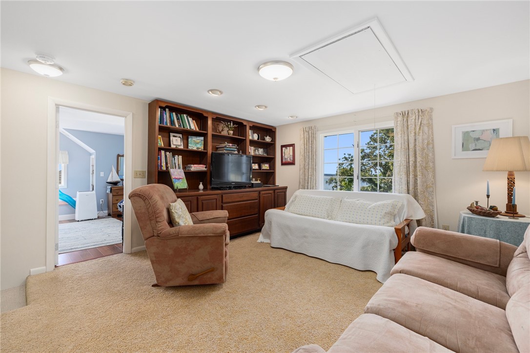 Living room with built-in wood shelving, television, and large window overlooking trees.