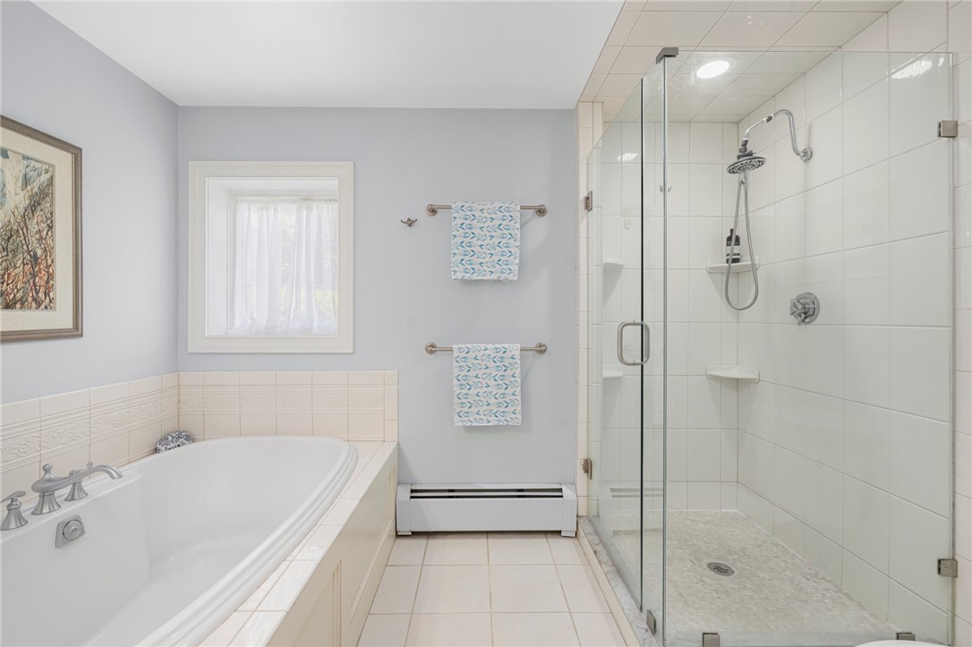 Bathroom with a corner soaking tub and glass-enclosed tiled shower.