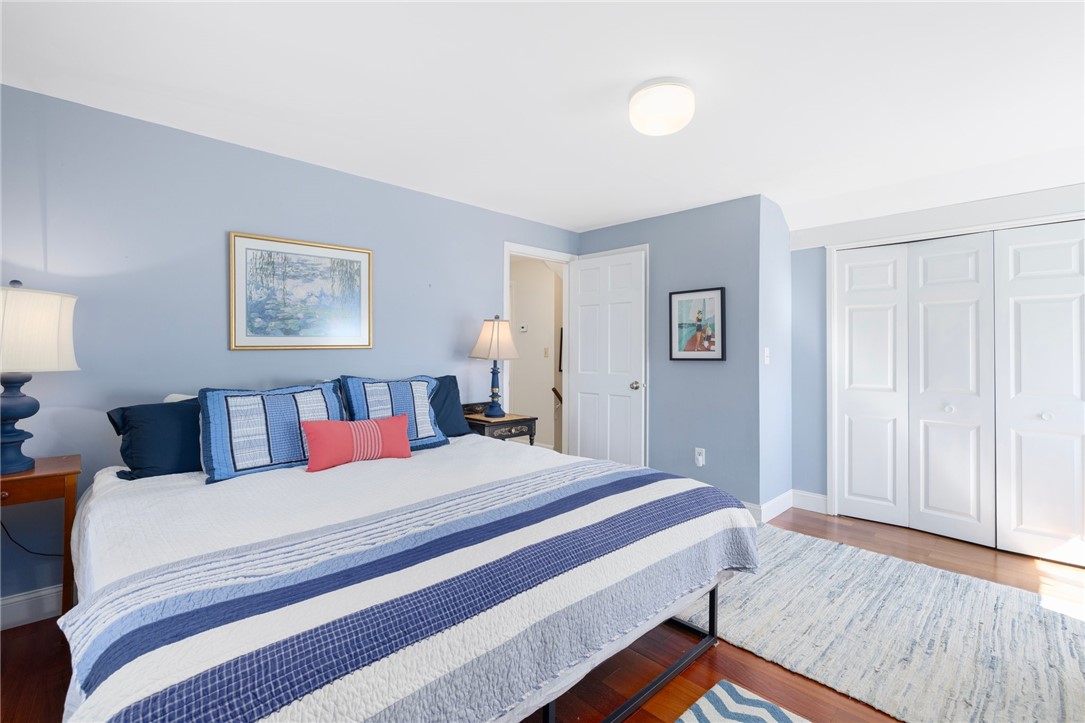 Bedroom with a blue-and-white striped bedspread, matching blue walls, and white closet doors.
