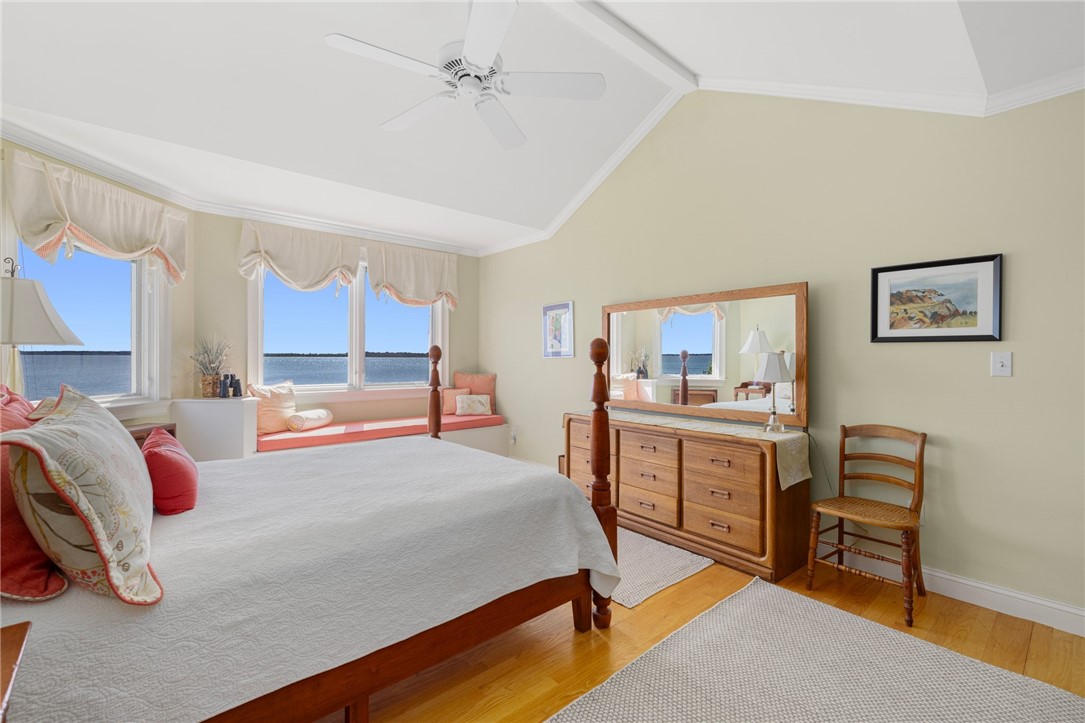 Bedroom with water views, a white bed, and a wooden dresser beneath a large mirror.