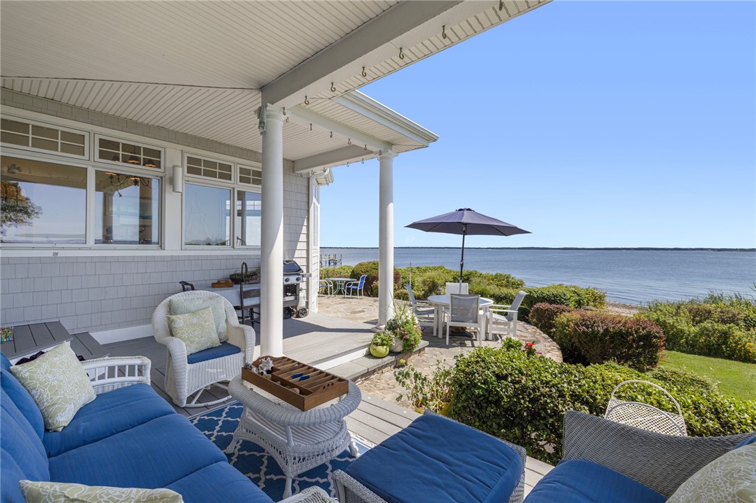 Furnished waterfront patio with blue seating, white columns, and bay views.