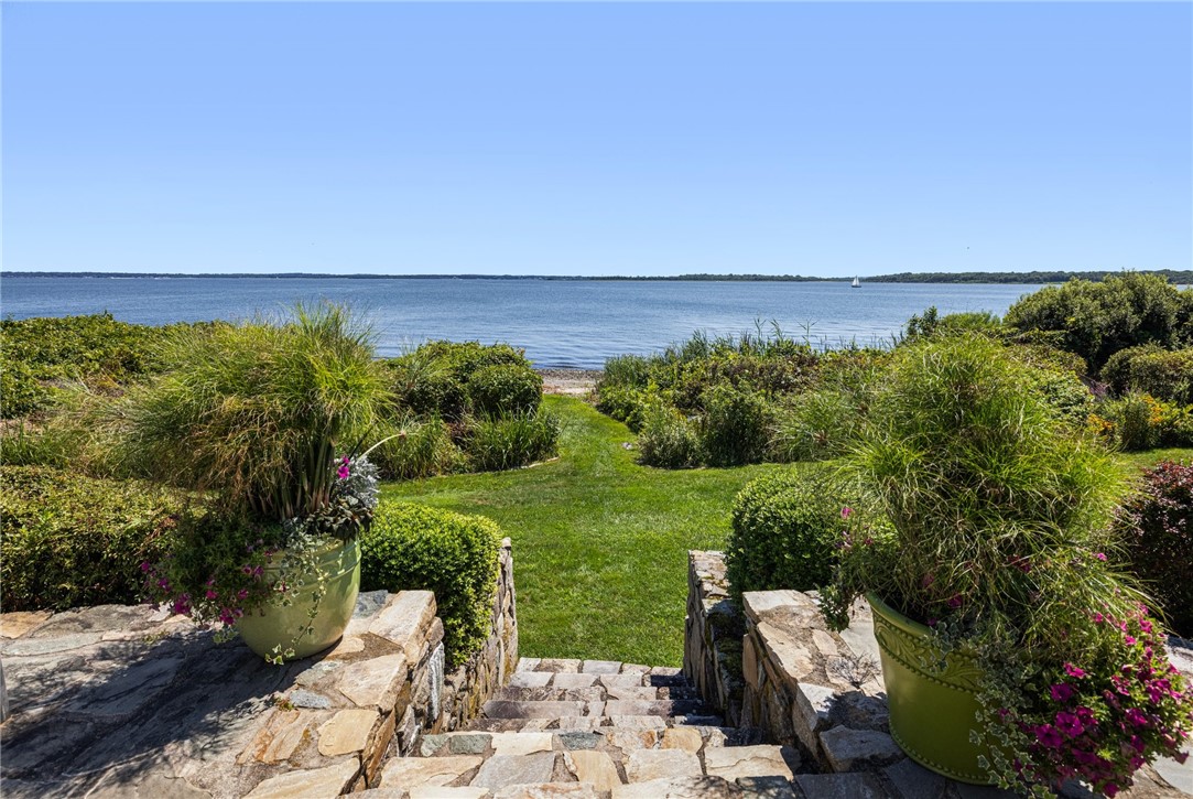 Landscaped stone steps lead through a garden to the water’s edge.