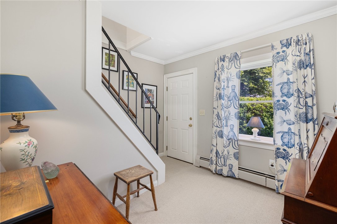 Entryway with a staircase, blue patterned curtains, and warm wood furniture.