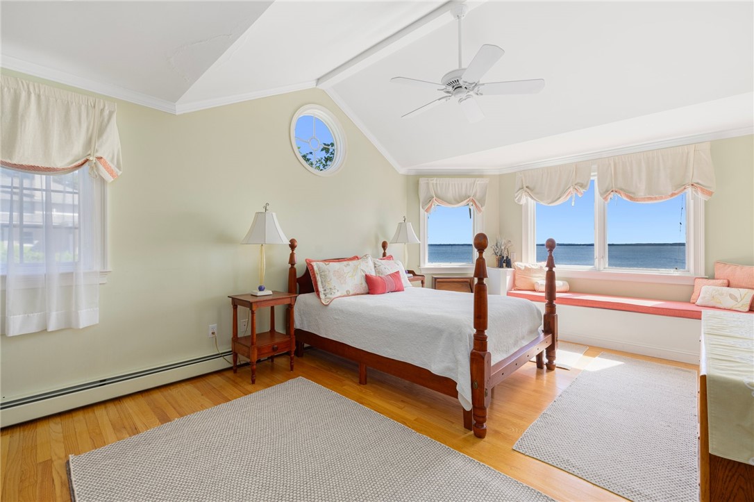 Bedroom with a four-poster bed, vaulted ceiling, and water views through wide windows.