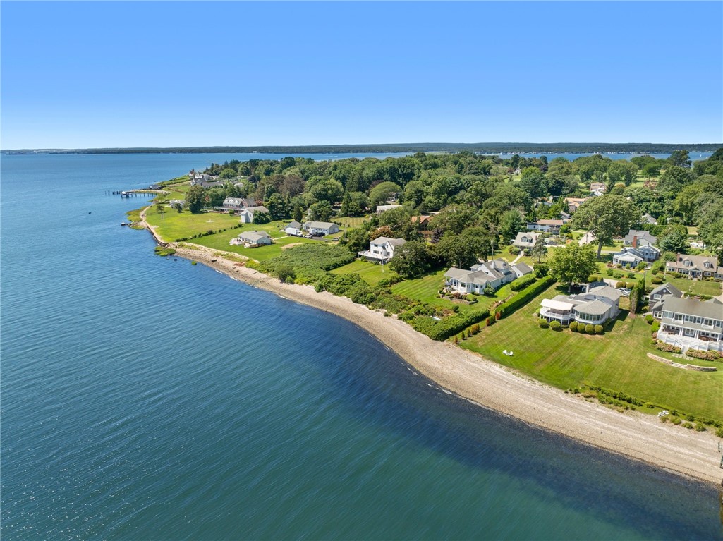Aerial view of waterfront homes along a curved shoreline on a sunny day.