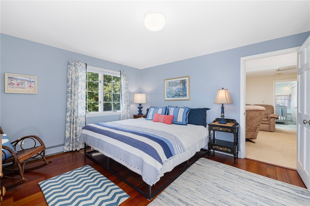 Bedroom with a blue-and-white bed, hardwood floors, and an open doorway to a sitting room.