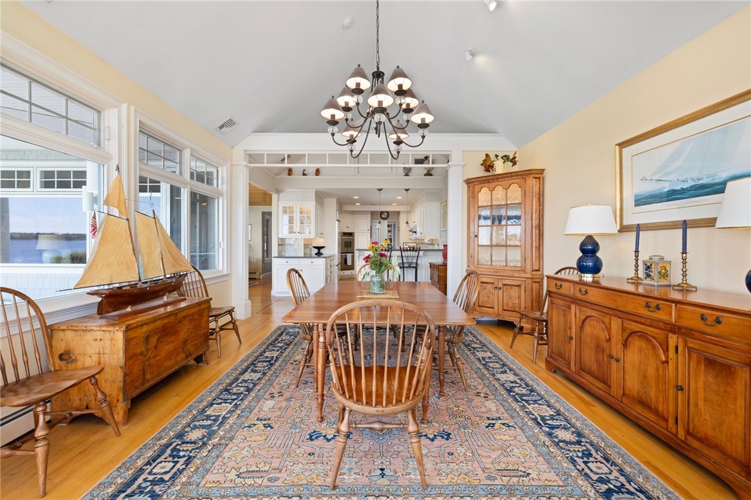Dining room with a wooden table, antique furnishings, and water visible through large windows.