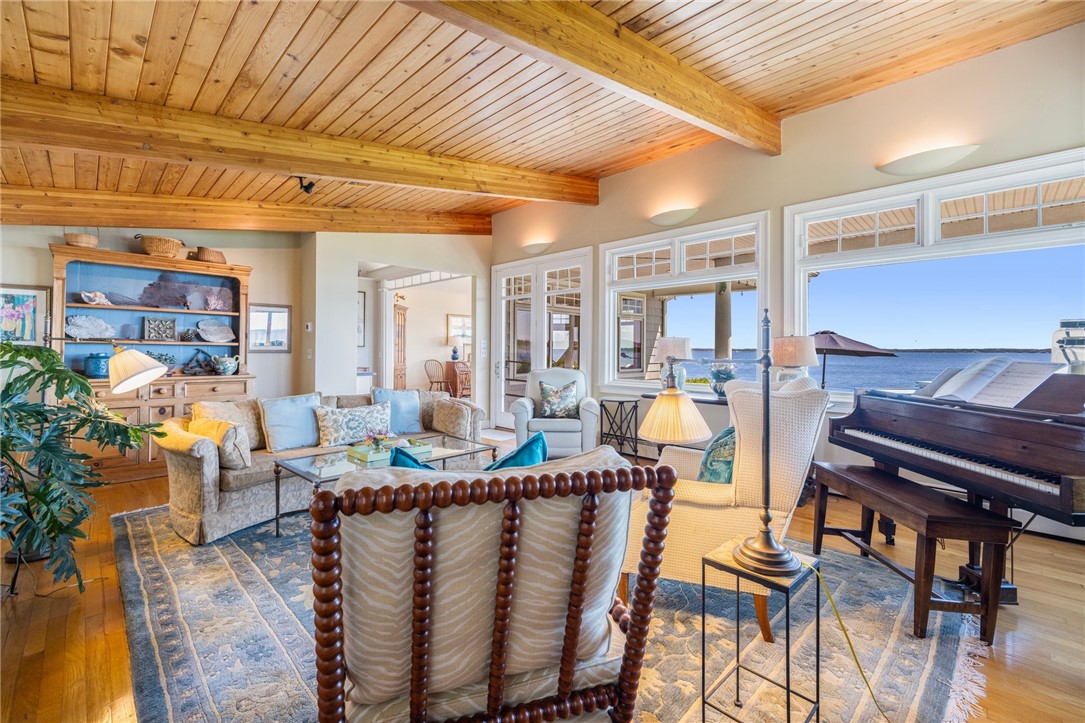 Living room with a beamed wood ceiling, piano, and expansive water views.