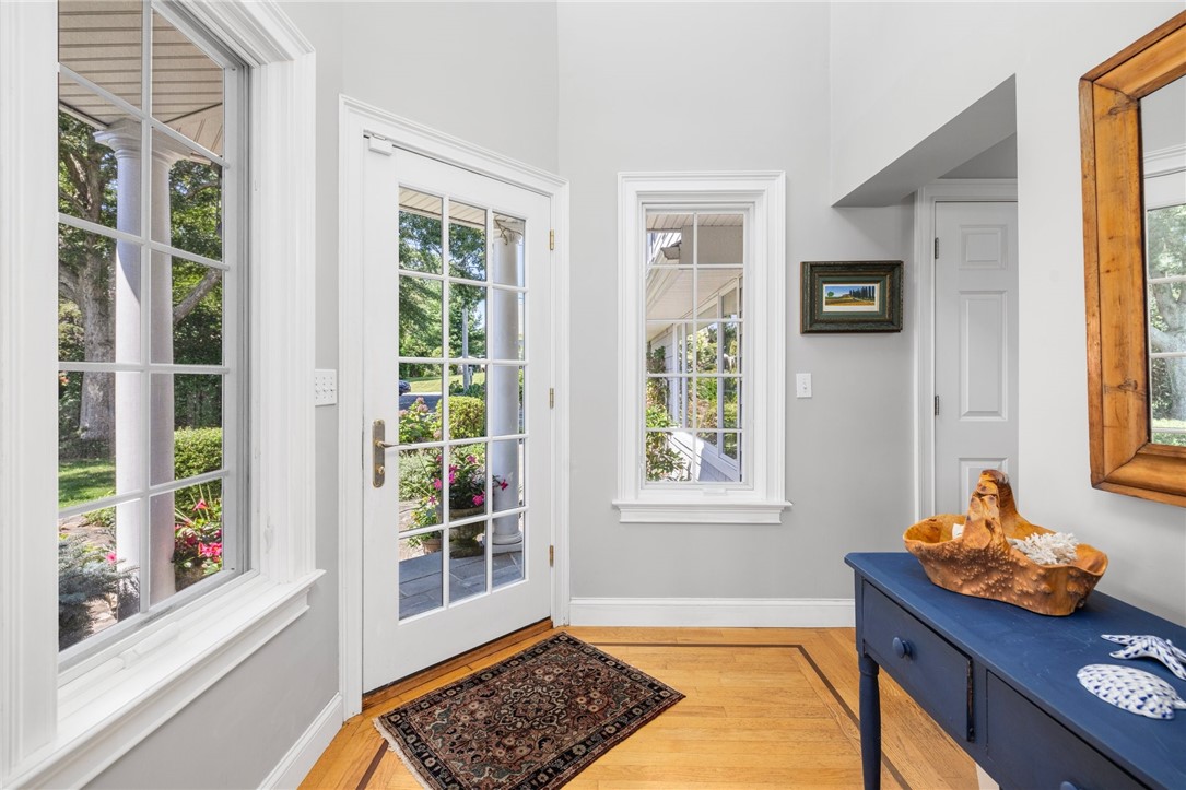 Bright entry foyer with a glass-paneled door, large windows, and hardwood floors.