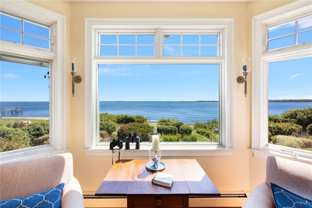 Sunroom seating area with expansive windows overlooking the water.