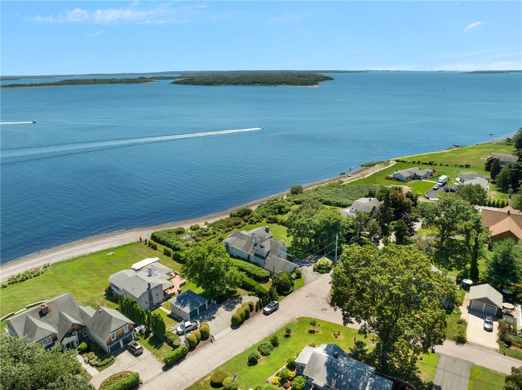 Aerial view of waterfront homes along a bay, with boats crossing the water.