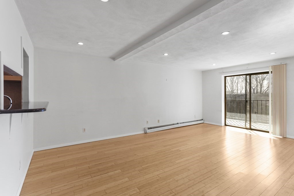 Vacant living room with hardwood floors and sliding glass doors opening to a balcony.