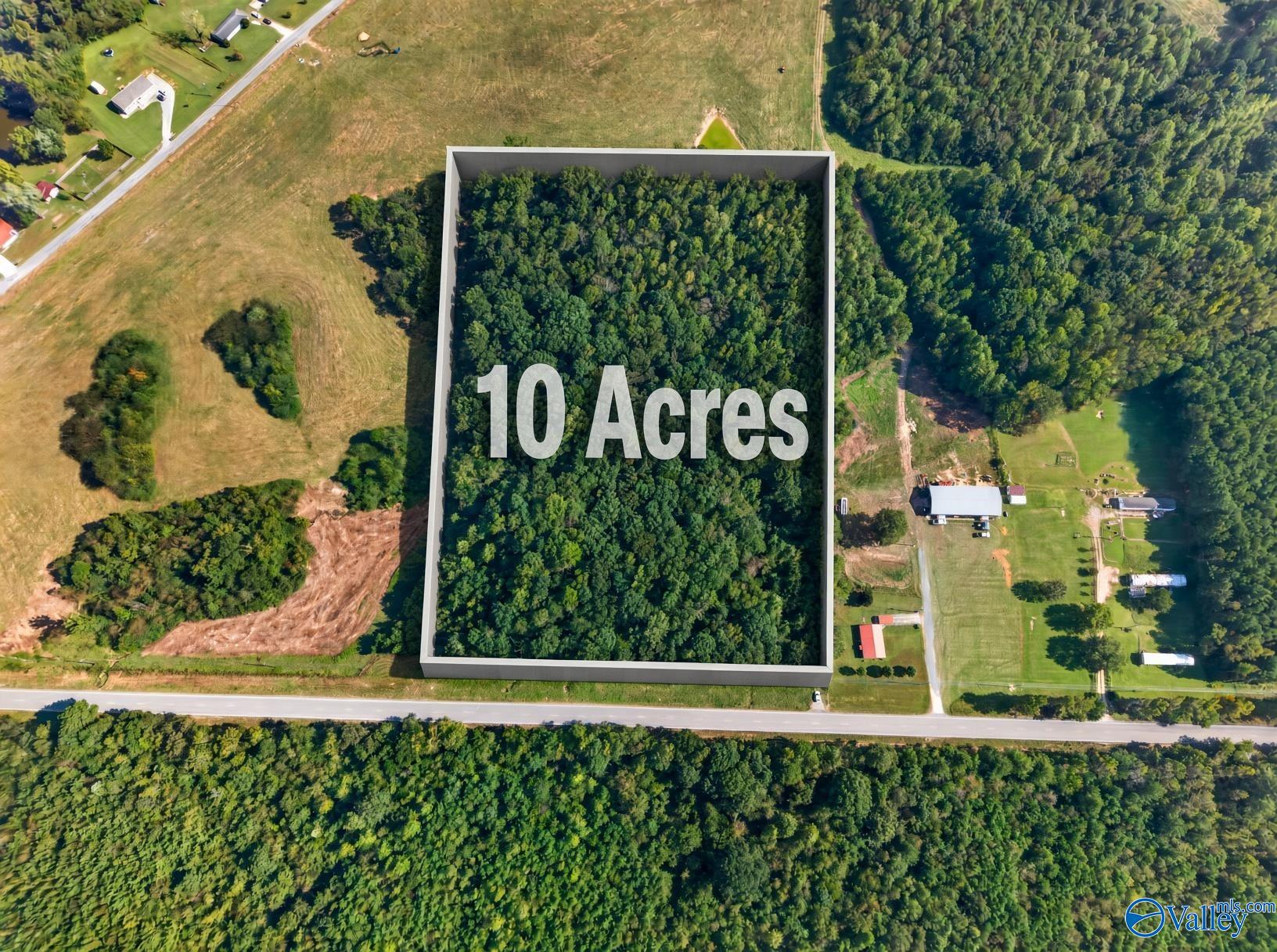 Aerial view of a wooded 10-acre parcel outlined beside a road.