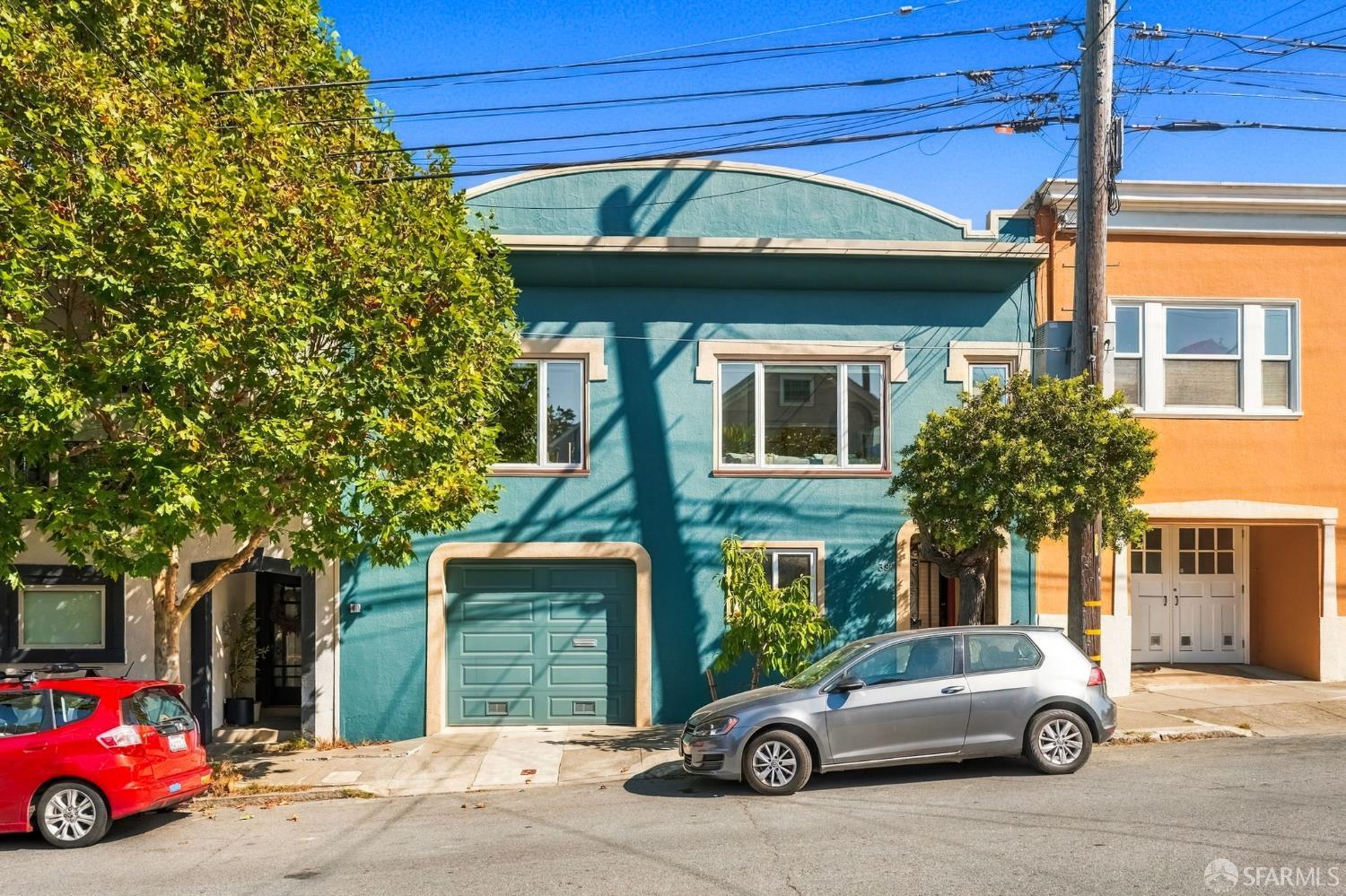 Teal two-story home with a matching garage door and cream trim on a sunny street.