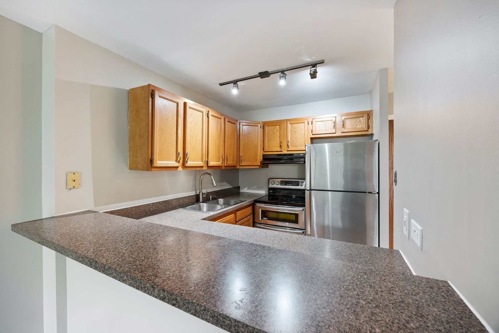 Kitchen with wood cabinets, a granite breakfast bar, stainless appliances, and a double-basin sink.