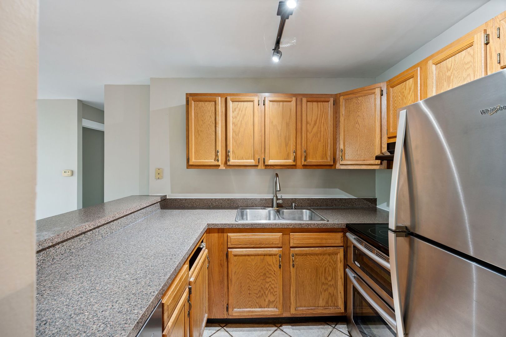 Kitchen with oak cabinets, speckled countertops, and stainless-steel appliances.