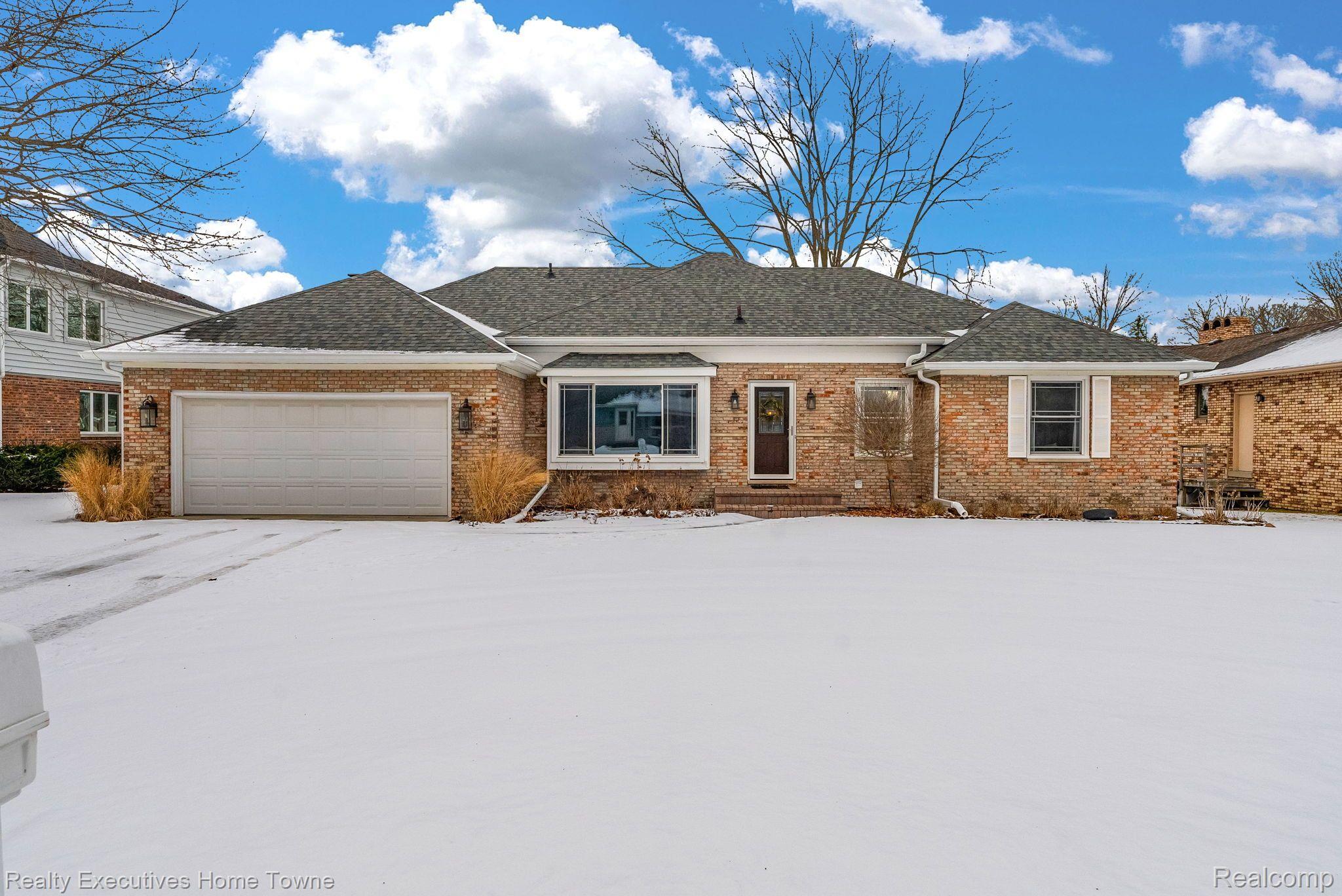 Single-story brick home with an attached garage and a snow-covered driveway.
