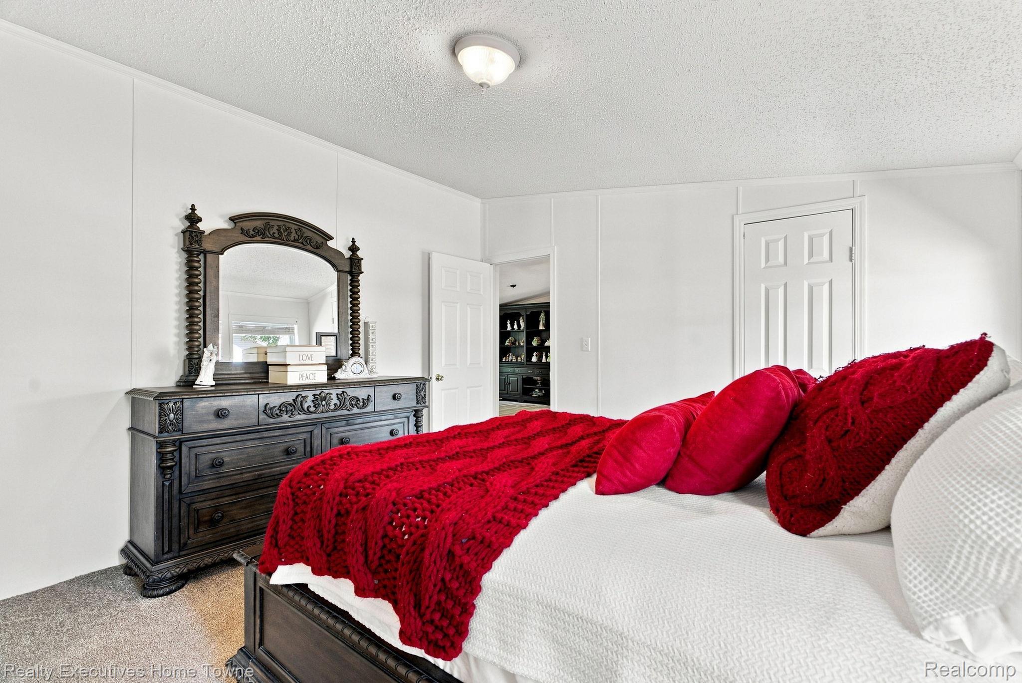 Bedroom with vivid red bedding and an ornate dark wood dresser and mirror.