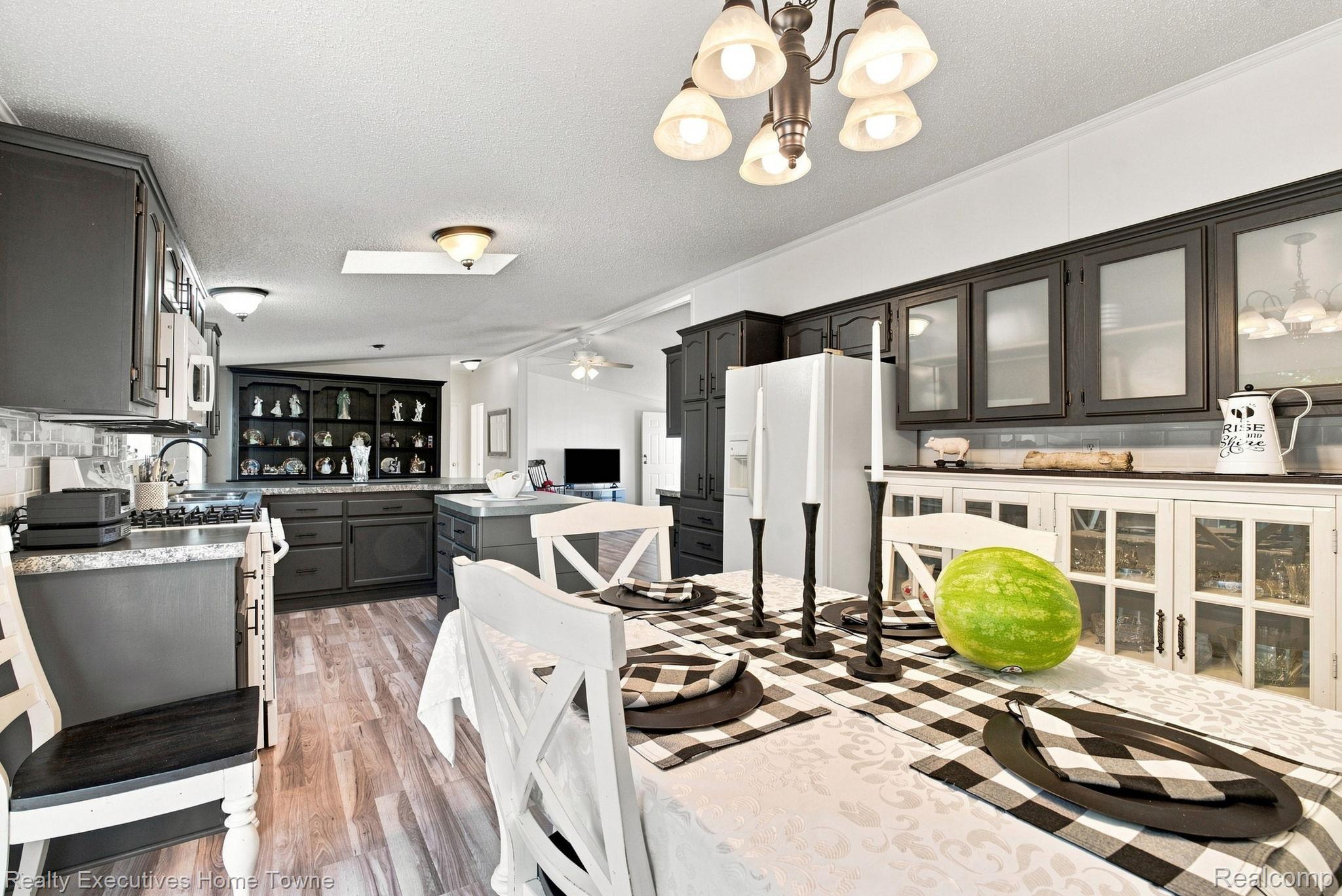 Kitchen and dining area with dark cabinetry, a central island, and a checkered table setting.