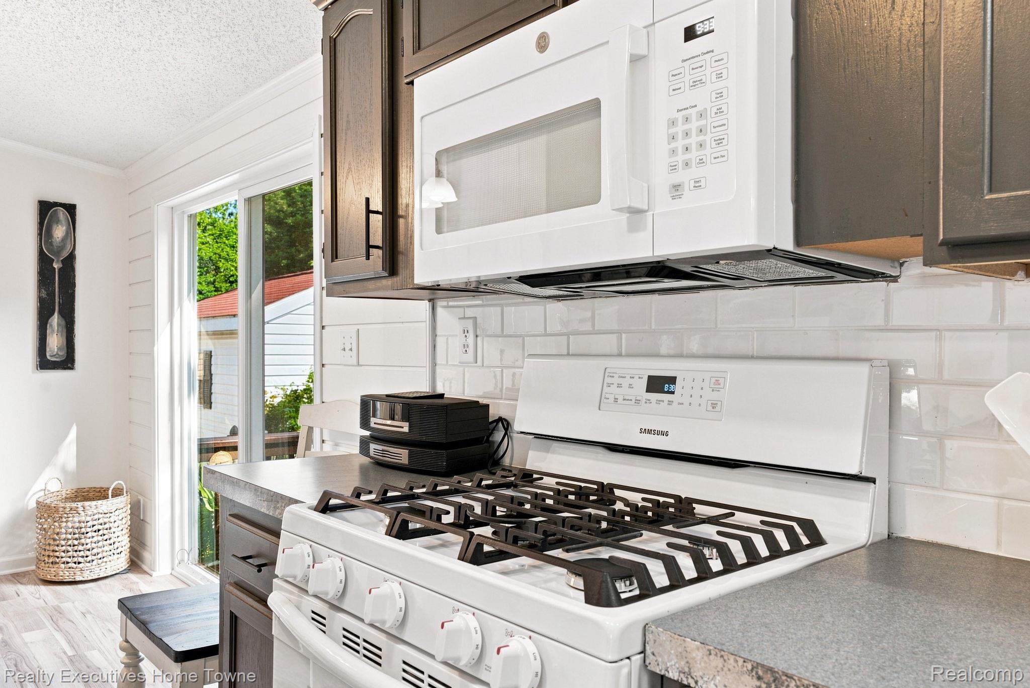 Kitchen with a white gas range, built-in microwave, dark wood cabinets, and a sliding glass door.