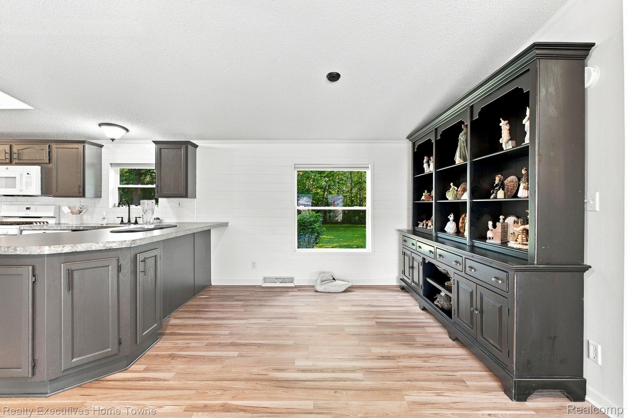 Kitchen with gray cabinets, wood-look flooring, and a built-in figurine display cabinet.