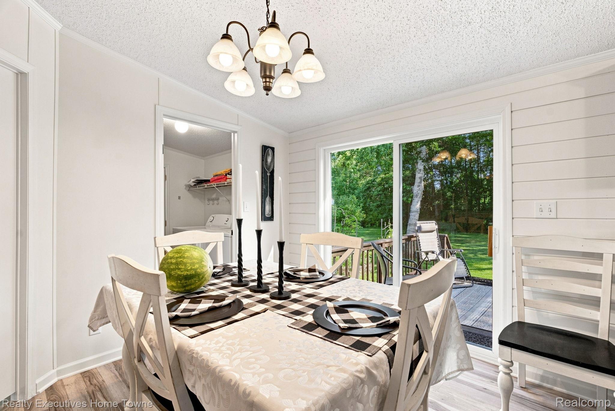 Dining room with a set table and sliding glass doors overlooking a deck and leafy backyard.