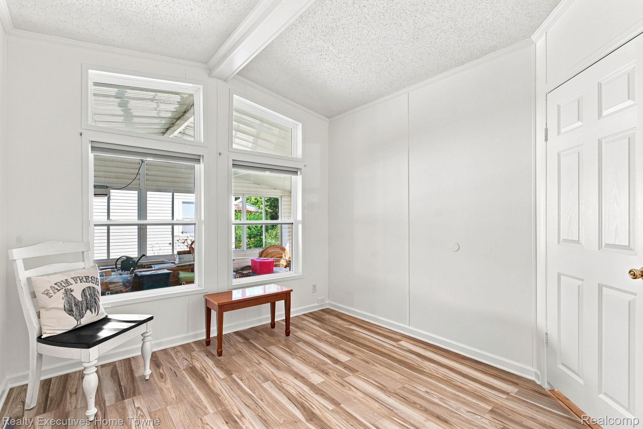 Bright room with wood-look flooring, porch-facing windows, a white chair, and a small table.
